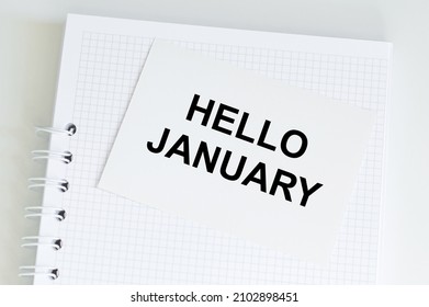 Hello January text on a card on the background of a notebook on the table - Powered by Shutterstock