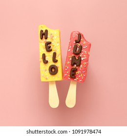 Hello June chocolate text and two ice creams with sprinkles on pink pastel background.