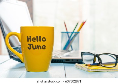 Hello June - inscription at yellow morning coffee or tea cup at business office background. First summer day, Calendar concept