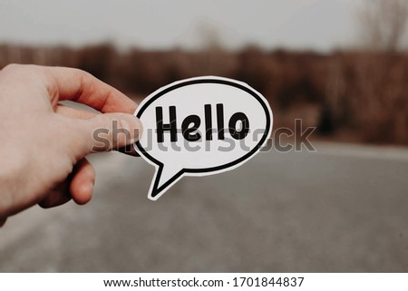 Hello in the left hand of a man standing on the road