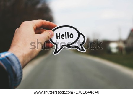 Hello in the left hand of a man standing on the road