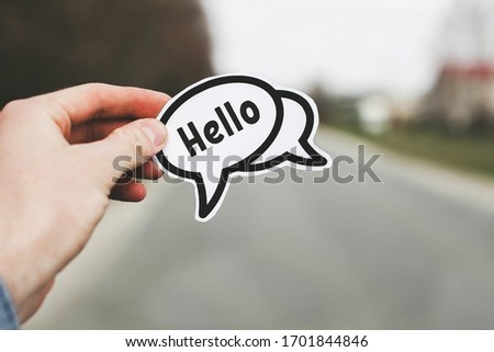Hello in the left hand of a man standing on the road