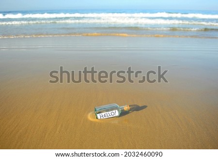 Hello! Message in a bottle. Greetings in a bottle on sand beach.