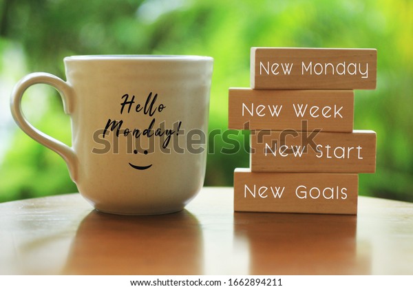 Hello Monday concept\
with inspirational quote on wooden blocks - New Monday. New Week,\
New Start. New Goals. And a smiling face on a white morning cup of\
coffee or tea.