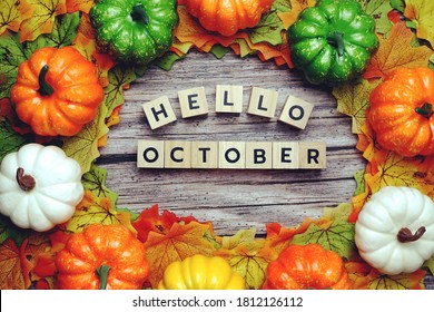 Hello October alphabet letter with pumpkin and maple leaves decoration on wooden background
