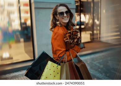 Hello september. smiling stylish woman in brown trench coat with shopping bags and autumn yellow leaves near shop in the city. - Powered by Shutterstock