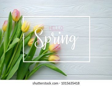 Hello Spring concept. Lovely tulip flowers on white wooden background. Flat lay, top view