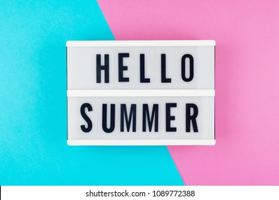 Hello Summer - text on a display lightbox on blue and pink bright background.