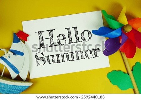 Hello summer text on paper card with colorful pinwheel top view on yellow background