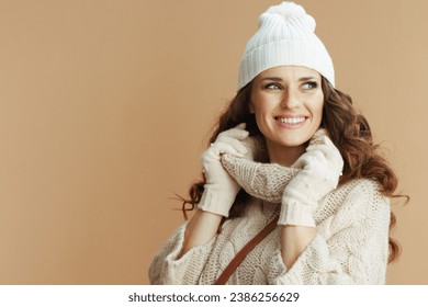 Hello winter. happy stylish middle aged woman in beige sweater, mittens and hat on beige background. - Powered by Shutterstock