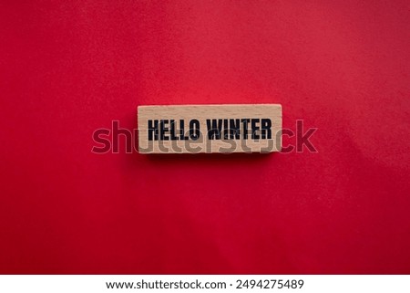 Hello winter message written on wooden block with redbackground. Conceptual hello winter symbol. Copy space.
