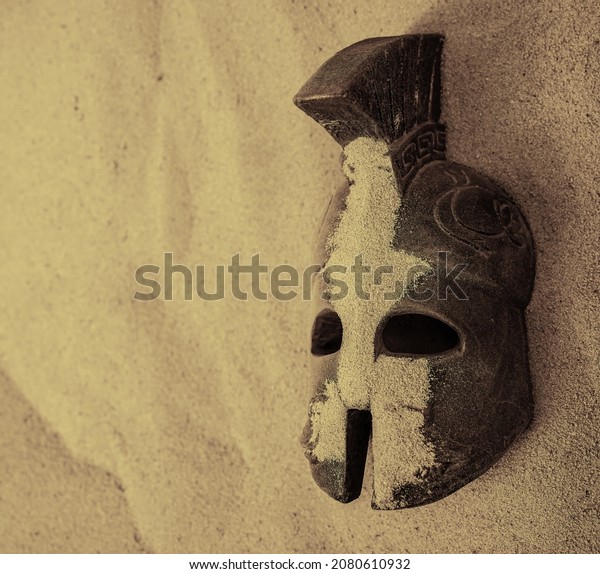 helmet of ancient warriors in sand. Roman\
Legionar\'s helmet with the Iroquois.Archeology and paleontology\
concept archaeological excavation ancient history achaeologists\
unearth ancient\
artifacts.