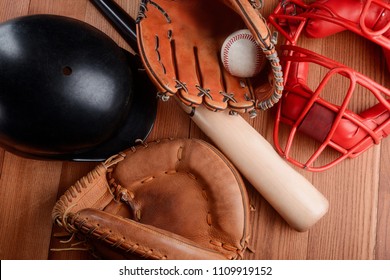 Helmet, Bat, Mitts And Ball On Wooden Background, Top View. New Baseball Arrivals At The Sport Goods Store.