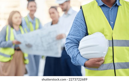 Helmet, construction and an architect standing on a building site with his team planning in the background. Leadership, architecture and renovation with an engineer holding a hard hat for maintenance - Shutterstock ID 2273722689