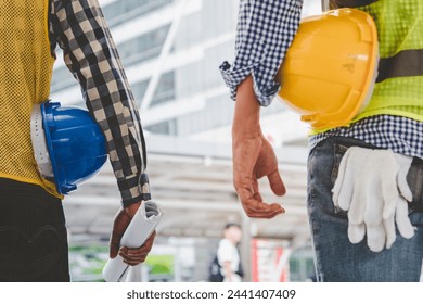 Helmet construction Engineer team. Men hands holding hardhat yellow work helmet in Civil Construction Engineering. Close up engineer man hold safety yellow worker helmet hard hat at Construction Site - Powered by Shutterstock