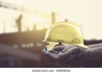 Helmet in hand at construction site with crane background
