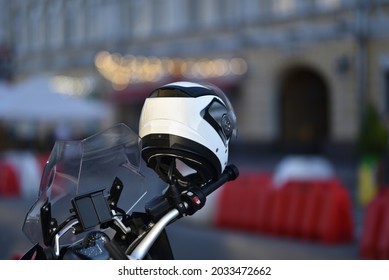 helmet hanging on motorcycle handlebar against traffic barriers in selective focus