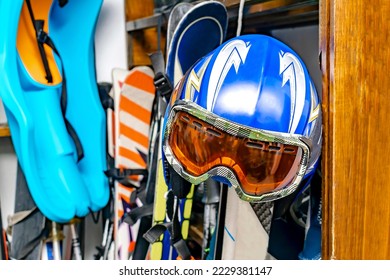 Helmet, ski mask, ski hanged on customized wooden wall mount at warehouse for seasonal storage at ski resort. Extreme winter sport equipment handling at home - Powered by Shutterstock