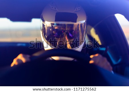 A Helmeted Race Car Driver At The Wheel