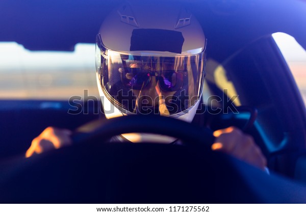 A Helmeted Race Car\
Driver At The Wheel