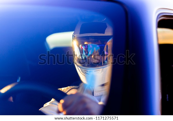 A Helmeted Race Car\
Driver At The Wheel