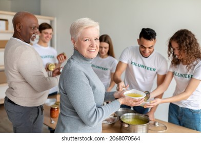 Help For Aged People. Volunteer Group Helping Feed Senior People With Free Meal And Giving Donation Boxes. Happy Elderly Woman Received Soup And Smiling To Camera