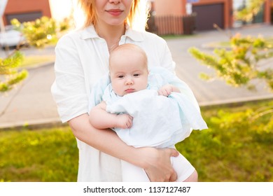 Help Babysitting For Busy Parents. Cropped Photo Of Nurse Is Holding A Pupil's Nursery. A Young Nanny Walks With A Baby Outdoors During An Evening Walk Before Dinner And Sleep