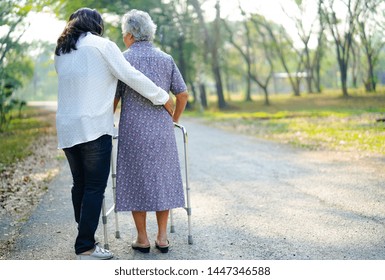Help And Care Asian Senior Or Elderly Old Lady Woman Use Walker With Strong Health While Walking At Park In Happy Fresh Holiday. 
