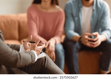Help Concept. Closeup Cropped View Of Man Counselor Therapist Or Consultant In Suit Talking With Couple Sitting In Office, Giving Professional Advice. Selective Focus On Hands With Clipboard And Pen