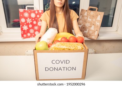 Help With Coronavirus Covid 19. A Volunteer Girl At A Charity Center Holds A Box Of Donation Food Products 