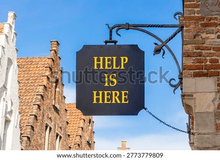 Help is here and support words symbol. Concept words Help is here on beautiful black road sign. Beautiful blue sky Brugge street background. Business help is here and support concept. Copy space.
