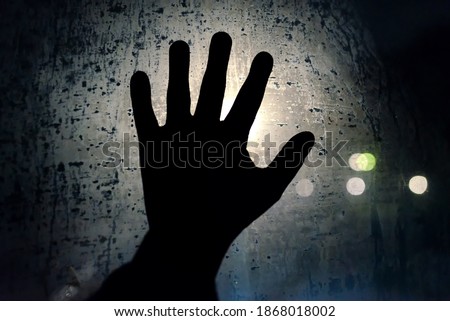 Help me. A hand calling for help on the foggy night glass window. Symbol of helplessness