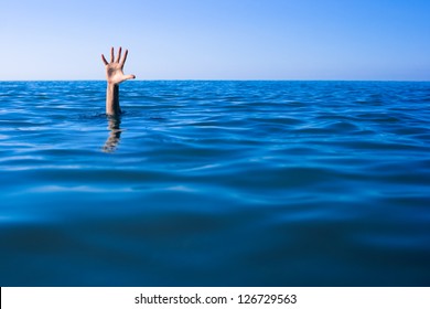 Help needed. Drowning man's hand in sea or ocean.