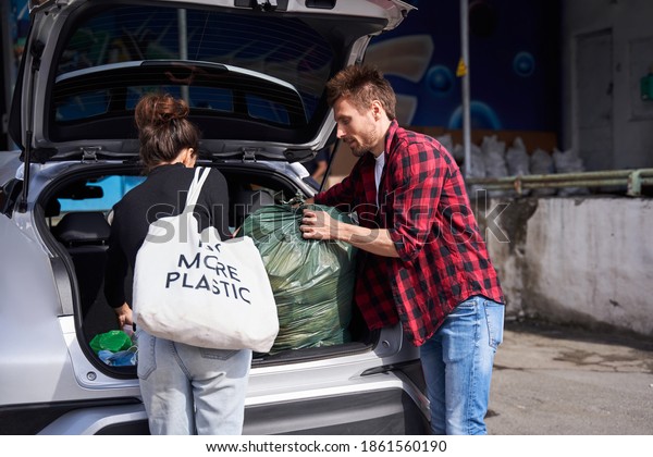 Help to our planet. Zero waste happy family\
unpacking their electrocar from the bags and plastic containers\
with wastes before they came to the garbage sorting factory.\
Recycling and ecology\
concept