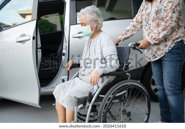 Help and support asian senior or elderly old\
lady woman patient sitting on wheelchair prepare get to her car,\
healthy strong medical\
concept.