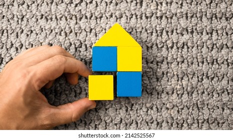 Help Ukraine. hand building home with wooden blocks with Ukraine flag colors