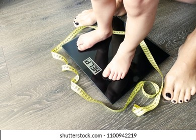 Help Your Child To Have A Healthy Diet And Lifestyle, With Obese Kid Feet On Weight Scale, Under The Supervision Of The Mother
