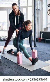 Helpful Female Coach Assisting Young Lady At The Gym With Correct Stretching Position