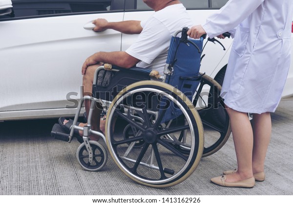  Helpful Female nurse with old man on\
wheelchair helping he get in to the car\
