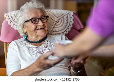 Helpful Home Healthcare Nurse Gives A Senior Female A Cup Of Hot Tea
