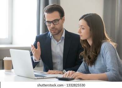 Helpful male boss mentor coach teacher explaining new online project to young female worker intern student, focused leader executive manager teaching student instruct trainee pointing at pc computer - Shutterstock ID 1332825530