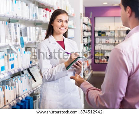 Helpful pharmacist serving and a consulting man in the pharmacy 
