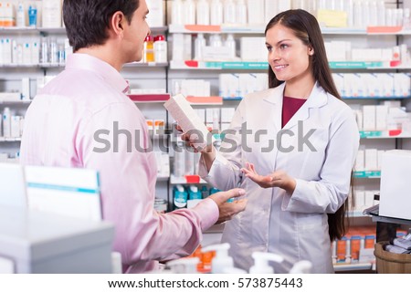 Helpful pharmacist serving and consulting man at a pharmacy 