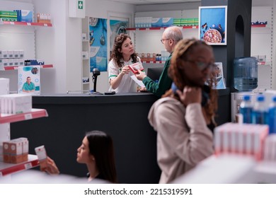 Helpful Pharmacy Worker Discussing About Medication Treatment With Elderly Client, Explaining Pills Leaflet During Medical Consultation. Customer Buying Supplements, Vitamin To Cure Disease