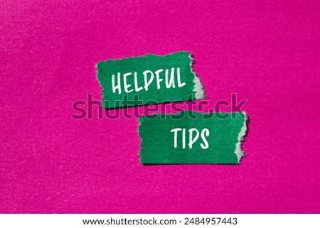 Helpful tips message written on ripped torn green paper pieces with pink background. Conceptual helpful tips symbol. Copy space.