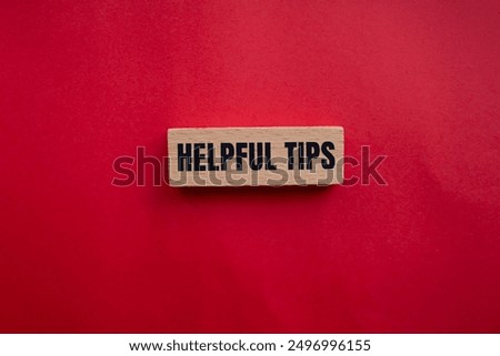 Helpful tips message written on wooden block with redbackground. Conceptual helpful tips symbol. Copy space.