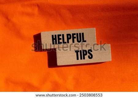 Helpful tips message written on wooden blocks with orange background. Conceptual helpful tips symbol. Copy space.