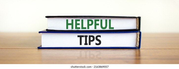 Helpful tips symbol. Books with words 'Helpful tips'. Beautiful wooden table, white background. Business and helpful tips concept. Copy space.