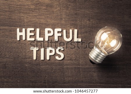 Helpful Tips text with glowing light bulb on wood texture