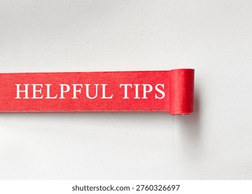 Helpful tips text on rolled red paper representing useful advice and practical guidance concept.